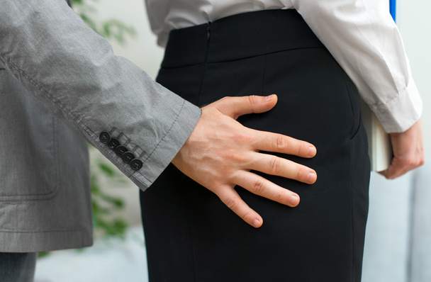 sexuelle Belästigung am Arbeitsplatz. Mann berührt Frau am Hintern. - Foto, Bild