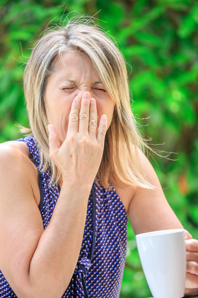 vrouw haar thee drinken en niezen verschuldigd aan allergische met groene b - Foto, afbeelding