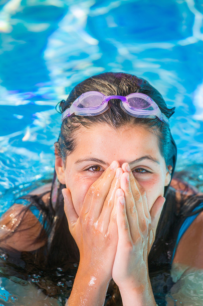Улыбающаяся девушка в бассейне кладет руки перед носом
 - Фото, изображение