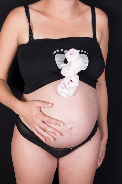 Woman holds her baby pink toe pregnant belly - Fotó, kép