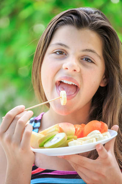 Bastante adolescente con ropa colorida comer frutas frescas en un g
 - Foto, Imagen