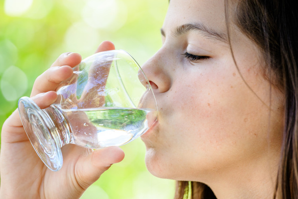 Nahaufnahme eines gesunden jungen Mädchens, das im Freien ein Glas Wasser trinkt - Foto, Bild