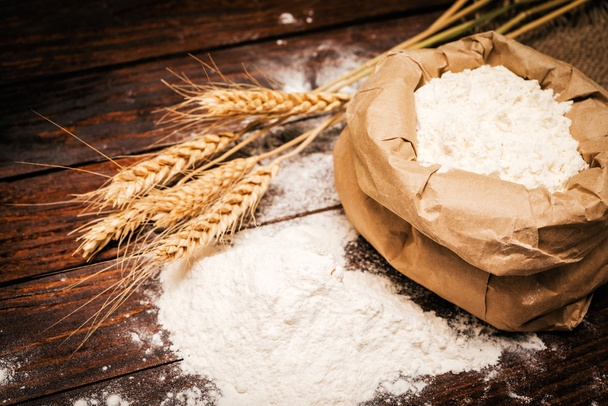 Wheat ears and flour on rustic background - Photo, Image