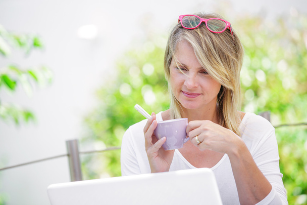 coffee break de loira madura atraente trabalhando em casa em seu jardim
 - Foto, Imagem