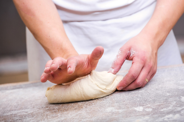 Primer plano de la mano de un panadero amasar y dar forma a la masa
 - Foto, imagen