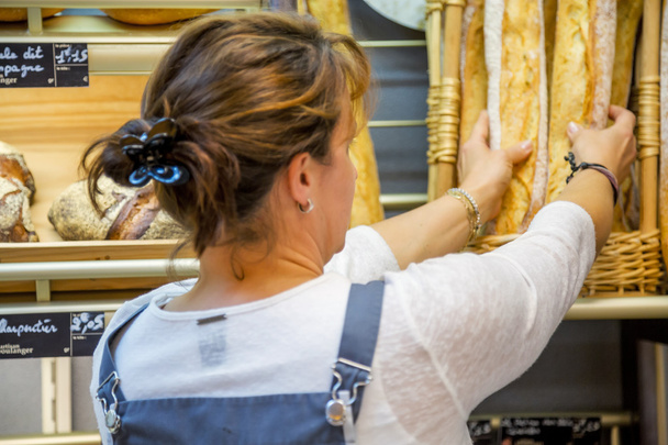 donna sorridente con un grembiule che vende pane in una panetteria
 - Foto, immagini