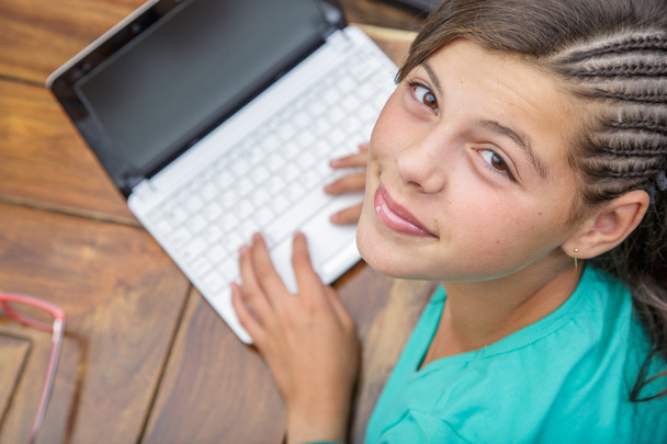 primer plano de niña bonita sonriendo que escribe en un teclado de ordenador visto desde arriba
 - Foto, Imagen