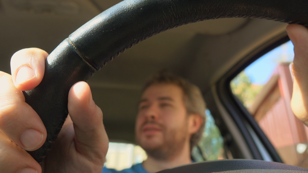 Homme joyeux mettant ses mains sur le volant de voiture, tir 4K
 - Séquence, vidéo