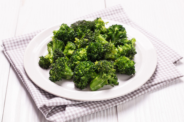 Bunch of fresh green broccoli on brown plate over wooden background - Фото, зображення