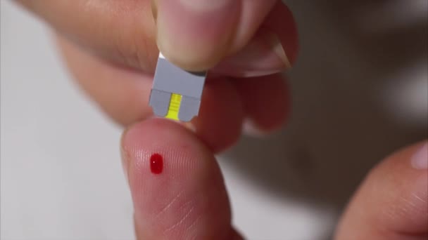 Vídeo macro de autoanálisis para la diabetes muestra de sangre está siendo tomada por un palo
 - Metraje, vídeo