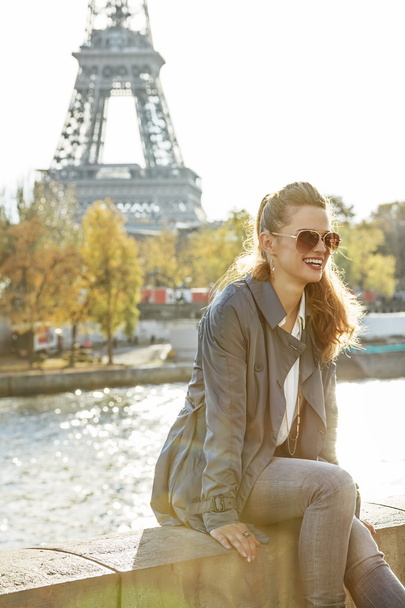 smiling elegant woman sitting on the parapet in Paris, France - 写真・画像