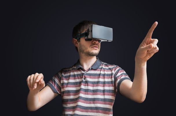 junger Mann trägt 3D-Virtual-Reality-Headset und berührt etwas - Foto, Bild