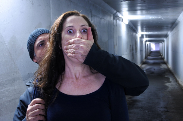 Чоловік нападає на жінку ззаду в темному тунелі
 - Фото, зображення