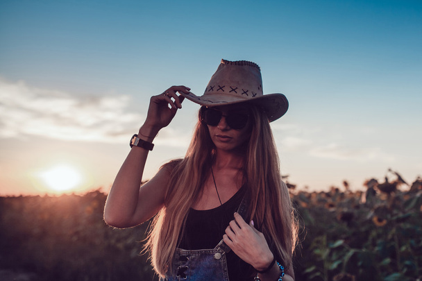 Lány egy cowboy kalapot, napraforgó mező. Naplemente - Fotó, kép