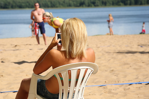 Blond dziewczyna siedzi na krześle na plaży - Zdjęcie, obraz