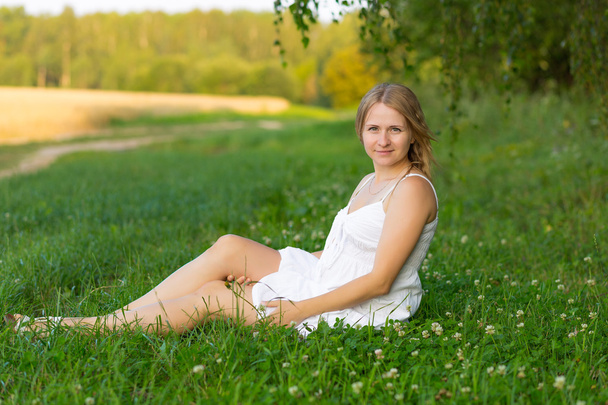 портрет вагітної жінки, що сидить на траві
 - Фото, зображення