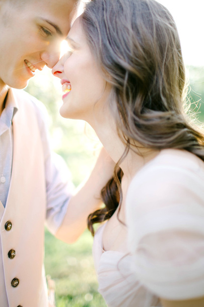 Portrait of beautiful young newlyweds outdoors over sunlight - Фото, изображение