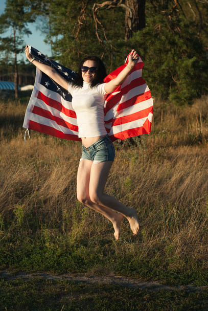 The girl with the American flag outdoors, stars and stripes flag flutters in the wind, - Φωτογραφία, εικόνα