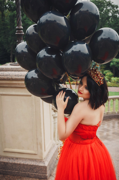 hinreißende Frau im roten Kleid mit schwarzen Luftballons - Foto, Bild