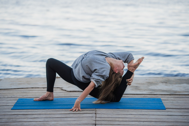 junge Sportlerin praktiziert Yoga am Strand - Foto, Bild