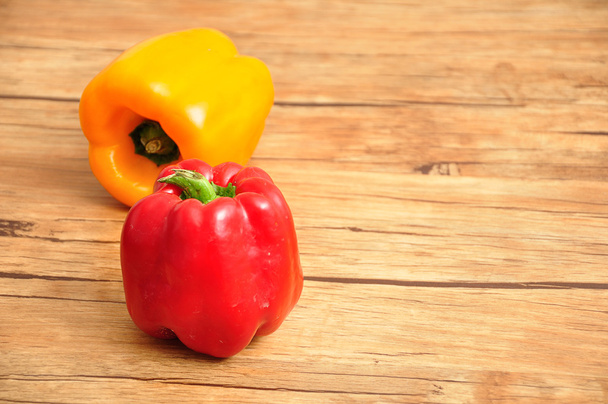 ein roter und gelber Paprika auf einem hölzernen Hintergrund - Foto, Bild