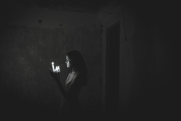 A girl holding a wax candle. Abandoned house. - Foto, Imagen