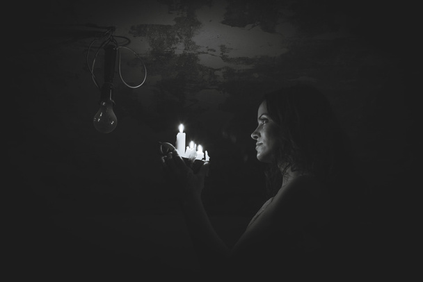Ella enciende una vela en una bombilla
 - Foto, imagen