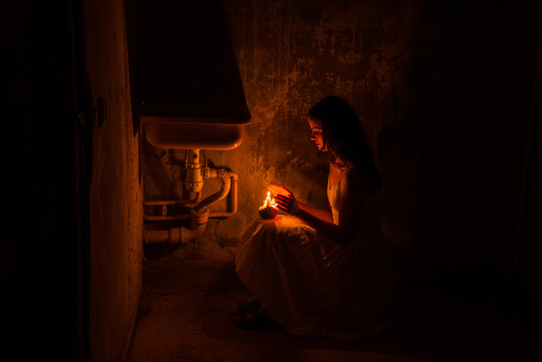 The girl warms hands with wax candles. Abandoned house. - Photo, Image