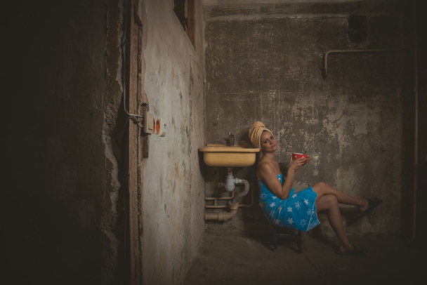 Cheap accommodation. Girl drinking tea in an old apartment - Фото, изображение