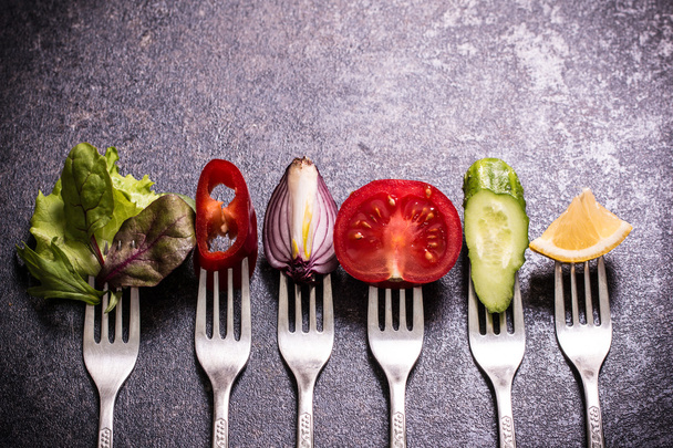 Fresh mixed vegetables on fork ,black background - Foto, afbeelding