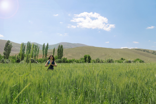 Happy woman in the young green wheat - 写真・画像