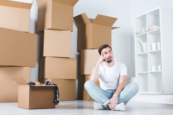 Moving in house. Man dreams sitting on the floor in the background box. - Photo, Image