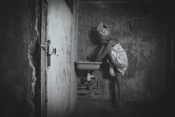 Cheap accommodation. The girl washing her feet in the sink. Blac - Foto, afbeelding