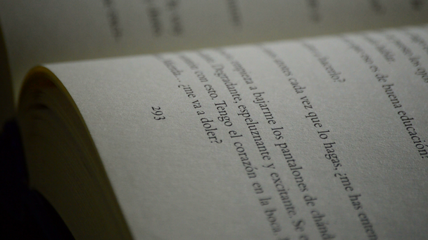 Textos, frases e palavras em espanhol de uma página de um livro aberto girando em um fundo preto
 - Filmagem, Vídeo