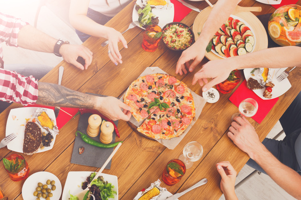 Οι άνθρωποι τρώνε πίτσα σε πάρτι εορταστικό τραπέζι - Φωτογραφία, εικόνα