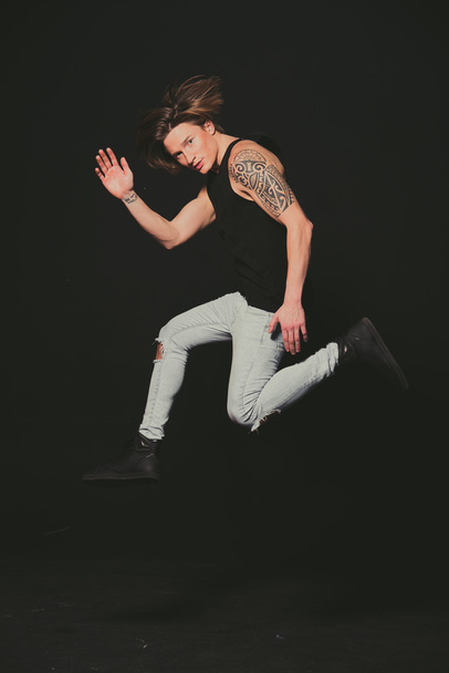 Model. Guy in a black shirt and jeans high jump. - 写真・画像