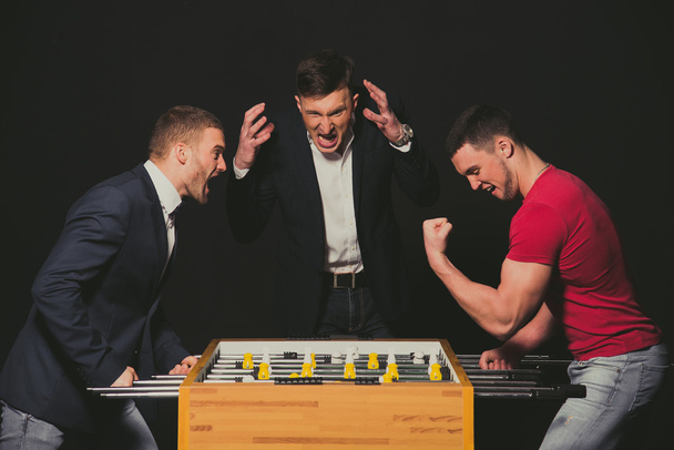 Boys play table football. The emotions of winning and losing. - Foto, afbeelding