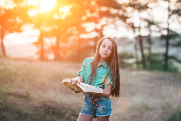 niedliches kleines Mädchen sitzt auf dem Gras und liest ein Buch in der  - Foto, Bild