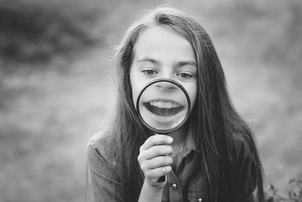 Το μικρό χαριτωμένο κορίτσι κοιτάζοντας μέσα από ένα μεγεθυντικό φακό - Φωτογραφία, εικόνα