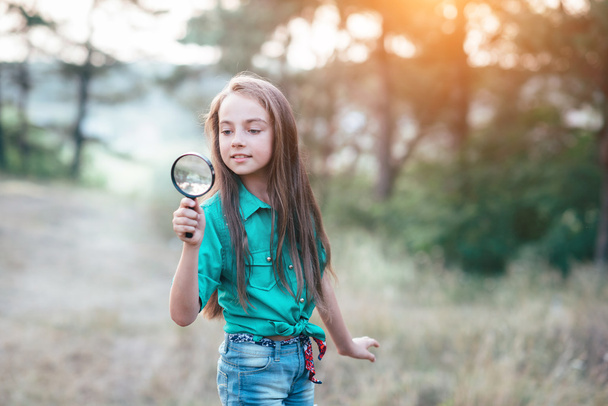 Little cute girl looking through a magnifying glass - Fotoğraf, Görsel