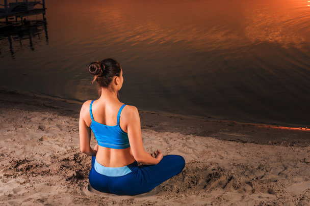 Yoga bij zonsondergang op het strand. - Foto, afbeelding