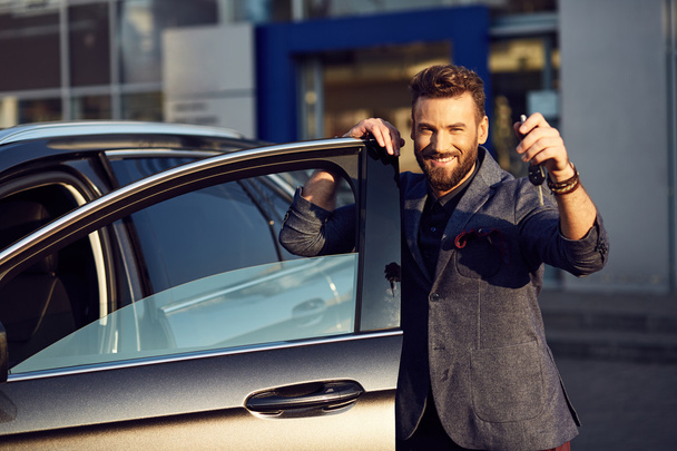 Handsome smiling man standing near car with key in his hand - Foto, immagini