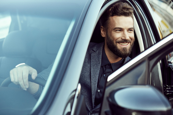 Handsome young man sitting and smiling in car - 写真・画像