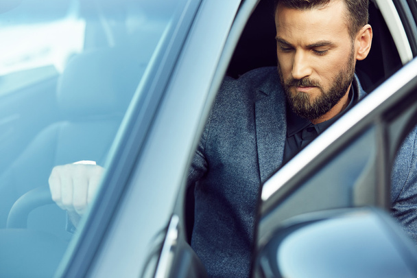 Handsome serious man sitting in car - 写真・画像
