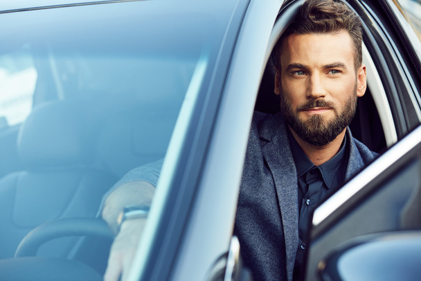 Attractive serious businessman posing in a car - Foto, Imagen