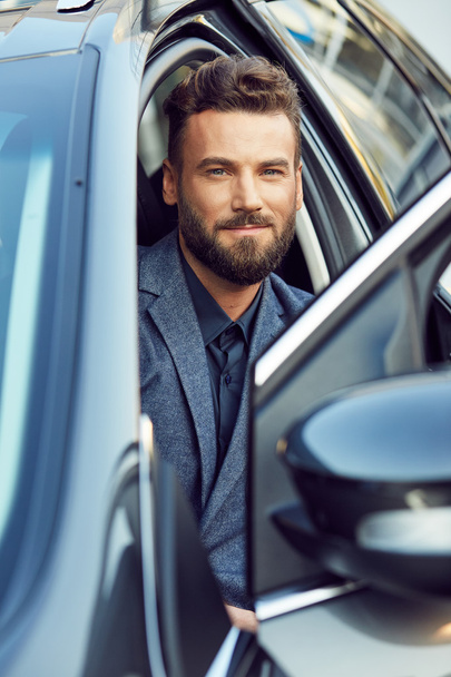Handsome man posing in a car on driver's place - Foto, afbeelding