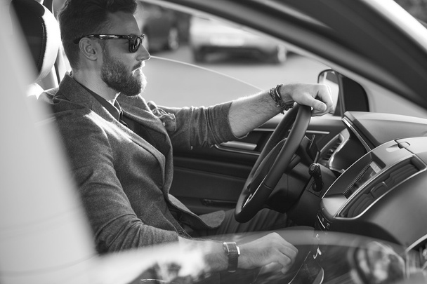 Handsome serious bearded man drives a car in black and white - Zdjęcie, obraz