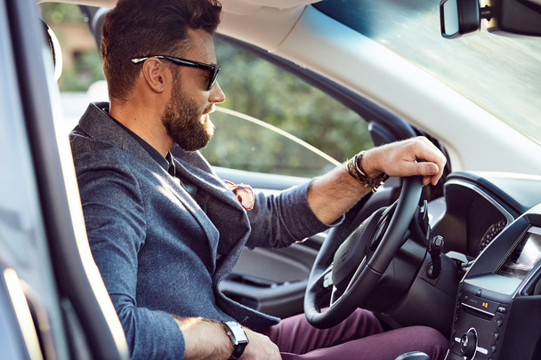 Гарний серйозний бородатий чоловік водить крутий автомобіль
 - Фото, зображення
