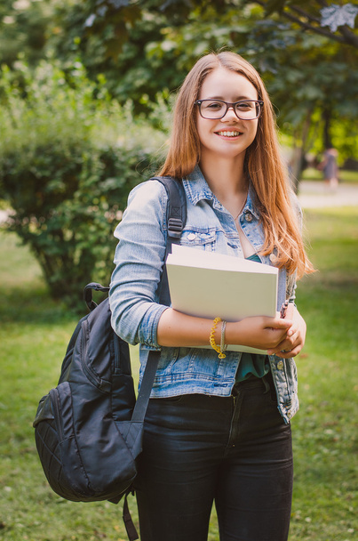 Ευτυχισμένος χαριτωμένο νεαρό χαμογελαστό κορίτσι φοιτητής στο πάρκο με τα βιβλία και - Φωτογραφία, εικόνα