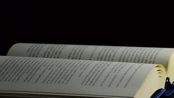 Stránky otevřené knihy rotují na černém pozadí - Záběry, video